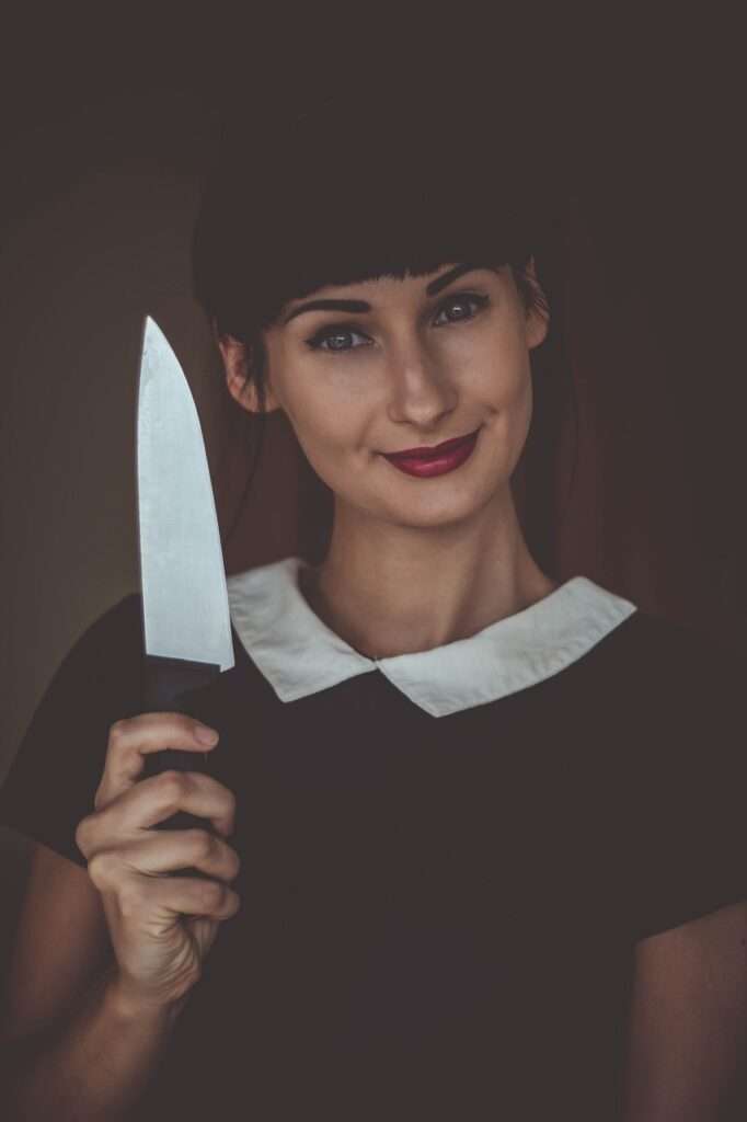 A woman holds a knife and smiles