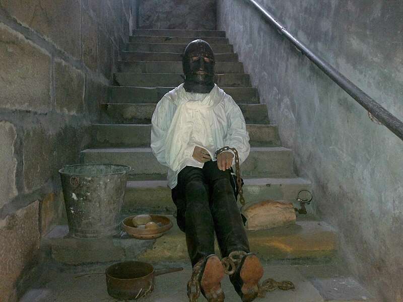 Man in the Iron Mask sits on stairs